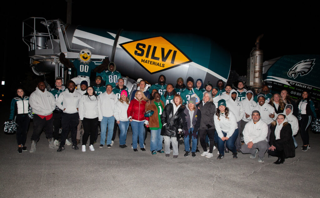 A photo of Silvi Materials staff and Philadelphia Eagles players in front of an Eagles-branded concrete mixer truck.