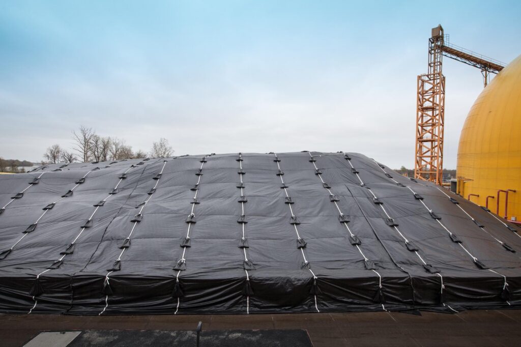 Bulk road salt stockpile covered with waterproof tarp to prevent moisture and clumping.